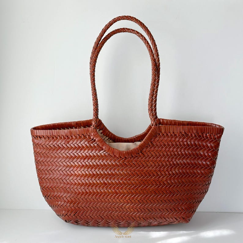 May include: A brown woven leather tote bag with braided handles. The bag has a wide, open top and a spacious interior. The leather has a rich, warm tone, and the weave pattern adds texture. A stylish and practical accessory for everyday use.