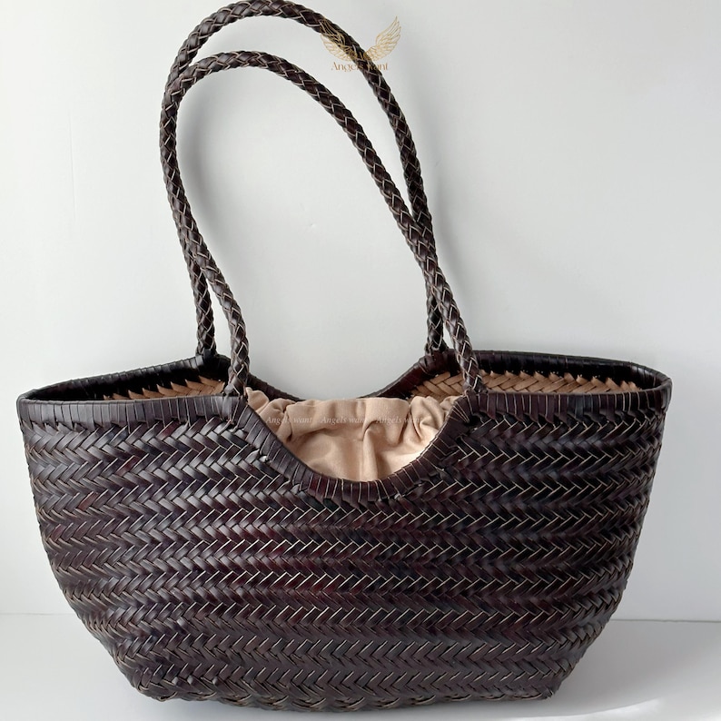 May include: A dark brown woven tote bag with braided handles. The bag has a spacious interior with a light tan fabric lining. The woven pattern creates a textured surface, and the handles are securely attached. This stylish bag is suitable for everyday use.
