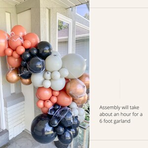 May include: A Halloween balloon garland in shades of orange, black, white, and gold. The garland is decorated with spiderwebs. Text on the right says, "Assembly will take about an hour for a 6 foot garland."
