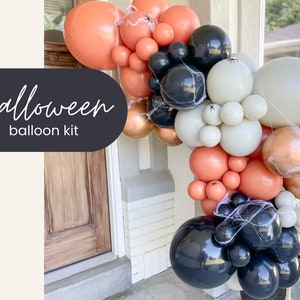May include: A Halloween balloon kit featuring a mix of orange, black, white, and bronze balloons. The balloons are arranged in an arch shape and decorated with spiderwebs and small plastic spiders. The text "Halloween balloon kit" is displayed on a dark oval.