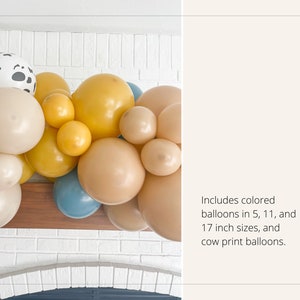 May include: A balloon garland featuring a mix of colors, including beige, yellow, and blue, with a cow print balloon. The garland includes balloons in 5, 11, and 17 inch sizes. The garland is displayed against a white brick wall.