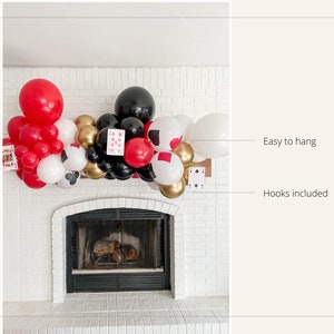 May include: A red, white, black, and gold balloon garland with playing card cutouts, hung above a fireplace. Easy to hang with hooks included.
