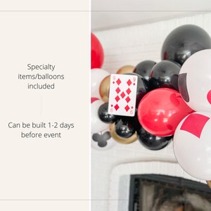 May include: A balloon garland with red, black, gold, and white balloons. The balloons have playing card symbols on them, including hearts, diamonds, spades, and clubs. The garland is hanging above a fireplace.