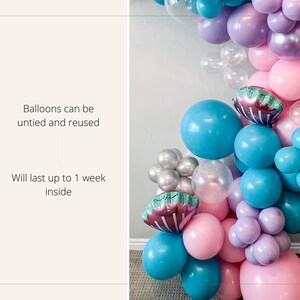 K&ouml;nnte beinhalten: Ein Ballonbogen aus pastellrosa, lila und blauen Ballons. Der Bogen ist mit schillernden Meerjungfrauen-Schwanz-Ballons verziert. Der Text "Balloons can be untied and reused" und "Will last up to 1 week inside" ist auf der linken Seite des Bildes sichtbar.