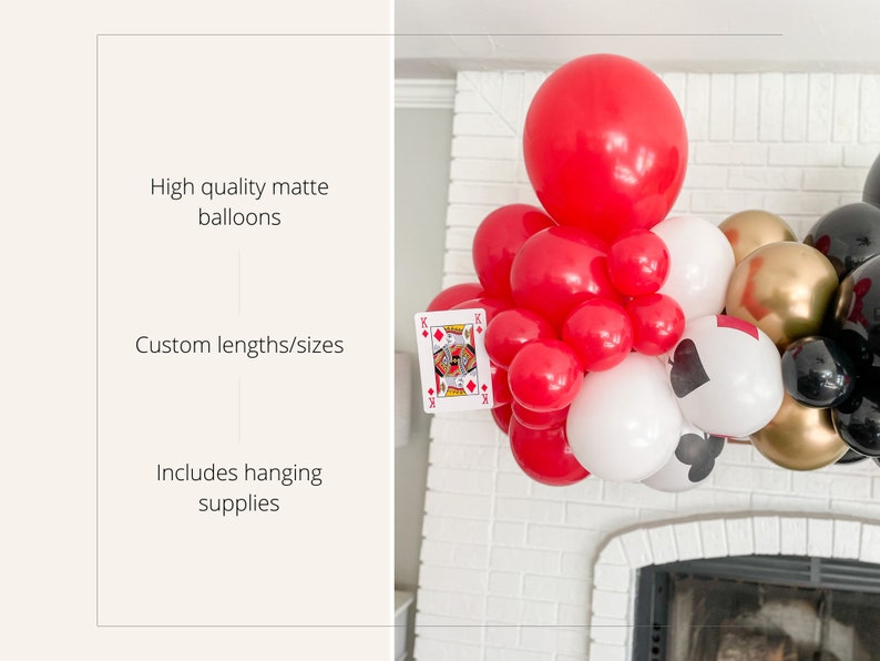 May include: A red, white, and black balloon garland with playing card cutouts. The garland is decorated with red, white, and black balloons, as well as gold and black balloons. The garland is hanging from a white brick wall.