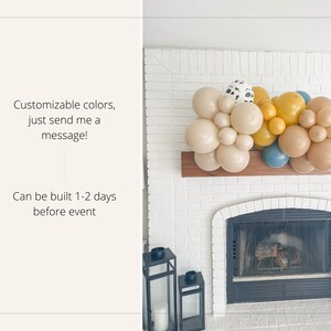 May include: A balloon garland in shades of beige, tan, yellow, and blue, with some balloons featuring a dalmatian print. The garland is displayed above a fireplace. Text on the left says, "Customizable colors, just send me a message!" and "Can be built 1-2 days before event."