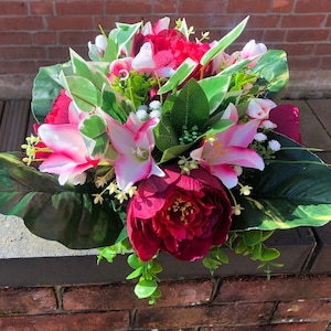 May include: A bouquet of artificial flowers with pink and white lilies, red peonies, and green leaves.