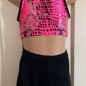 Peut inclure: Un soutien-gorge de sport rose et noir avec un motif géométrique argenté et un short noir assorti.