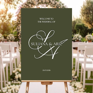 Könnte beinhalten: Ein olivgrünes Hochzeits-Willkommensschild auf einer Holzstaffelei. Auf dem Schild steht "WELCOME TO THE WEDDING OF SULIANA & ARIZ" in eleganter weißer Schrift, darunter das Datum "20.09.2026". Der Hintergrund zeigt eine Gartenkulisse mit weißen Stühlen.