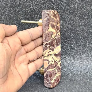 Handheld half moon marble cabinet handle showing real size, natural brown marble with gold veining and brass screw fittings