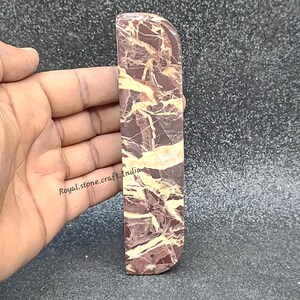Front view of straight marble door handle held in hand, natural brown marble with golden veining showing real size and polished stone finish