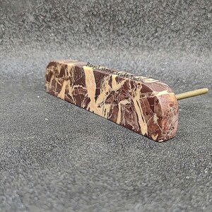 May include: A rectangular cabinet pull with a marble-like pattern in shades of brown and cream. The pull has a brass-colored stem extending from one end. The text "Royal Stone Craft India" is visible on the pull.