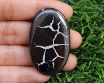 Könnte beinhalten: Ein ovaler Cabochon mit einem dendritischen Muster in Schwarz und Weiß. Der Stein ist hochglanzpoliert und in einer silbernen Fassung gefasst.