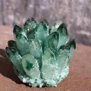 May include: A cluster of green quartz crystals, also known as green amethyst, with a natural, raw, and unpolished finish.