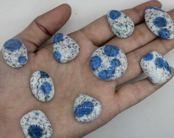 May include: A collection of eight polished blue and white speckled stones. The stones are smooth and have a variety of shapes and sizes.