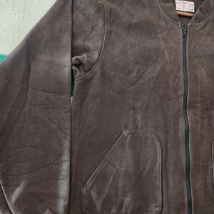 Peut inclure: Veste de bombardier marron avec une fermeture &eacute;clair noire et deux poches avant. La veste a un poignet c&ocirc;tel&eacute; et une &eacute;tiquette sur le col int&eacute;rieur. La veste est faite d'une mati&egrave;re douce semblable &agrave; du daim.