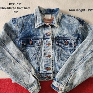 May include: Acid wash denim jacket with button fastenings, two chest pockets, and two side pockets. The jacket has a collar and long sleeves. PTP - 48 cm, shoulder to front hem - 41 cm, arm length - 56 cm.