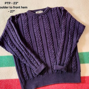 May include: A dark purple cable knit jumper with a crew neck and ribbed cuffs and hem. The jumper's measurements are PTP - 58 cm and shoulder to front hem - 69 cm.