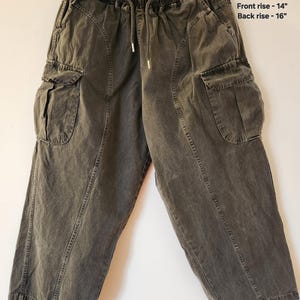 May include: Dark grey cargo trousers with an elasticated waistband and drawstring. Features two large side pockets and a relaxed fit. Measurements: Waist - 66 cm, Hip to cuff - 91 cm, Inseam - 61 cm, Front rise - 36 cm, Back rise - 41 cm.