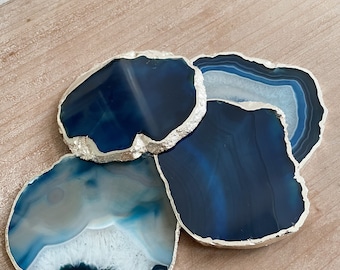 May include: Four blue agate coasters with silver trim. The coasters are irregularly shaped and have a natural, organic look.