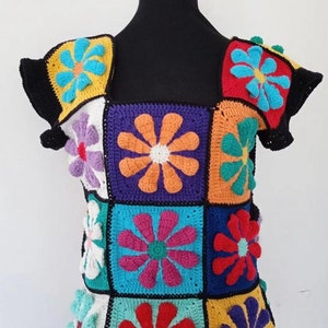 May include: A colorful crochet top with a square pattern of flowers in various colors, including red, orange, yellow, green, blue, purple, and white.