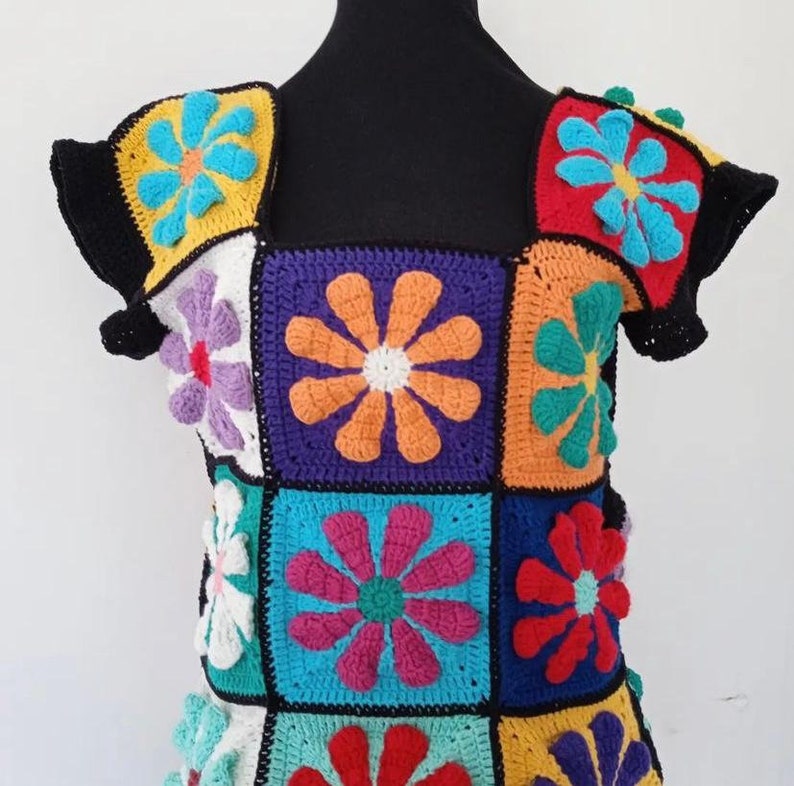May include: A colorful crochet top with a square pattern of flowers in various colors, including red, orange, yellow, green, blue, purple, and white.