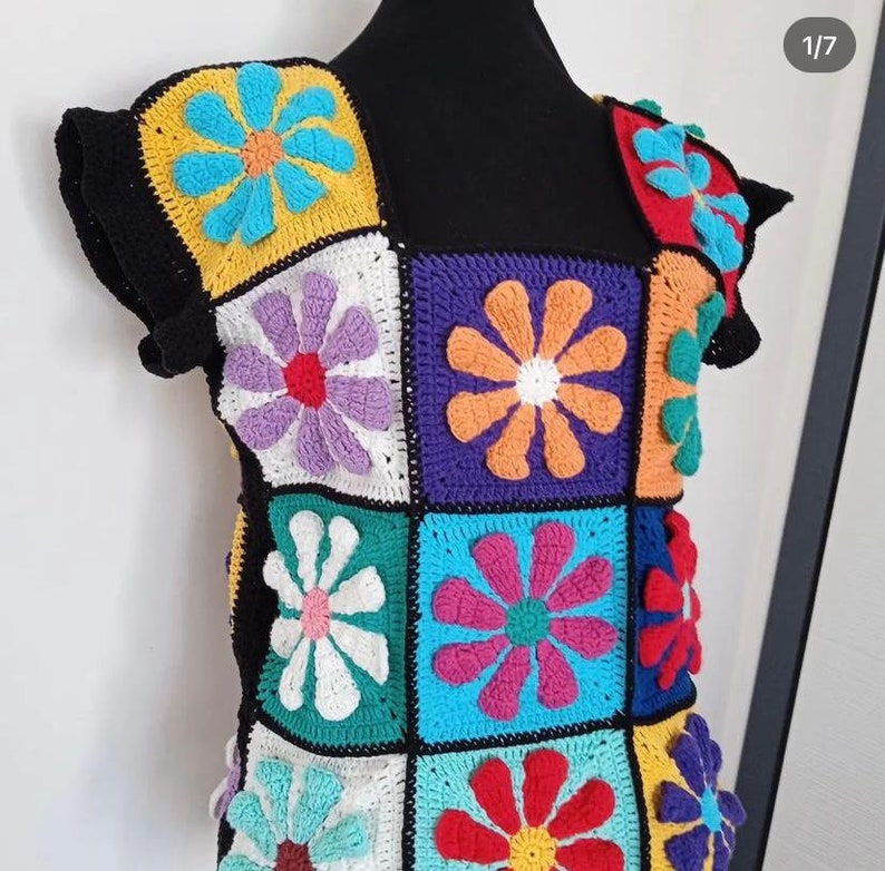 May include: A colorful crocheted top with a square pattern of flowers in various colors, including purple, blue, green, yellow, orange, and red.
