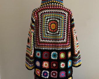 May include: A colorful crocheted cardigan with a hood. The cardigan is made of a black yarn with a multi-colored granny square pattern.