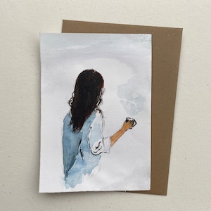 Könnte beinhalten: Aquarellmalerei einer Person mit langen dunklen Haaren, die ein hellblaues Hemd trägt und eine Tasse Kaffee hält. Der Hintergrund ist hellgrau.