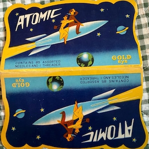 以下が含まれることがあります： ヴィンテージAtomic Gold Eyeの針パック。各パックには、宇宙をロケットに乗って移動するカップルのレトロなイラストが描かれています。パックには85本の針と糸通しが含まれています。日本製。