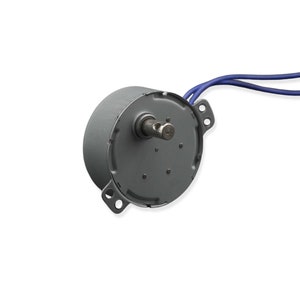 Könnte beinhalten: Ein kleiner, grauer Elektromotor mit zylindrischem Gehäuse und einer herausragenden Welle. Zwei blaue Drähte gehen vom Motor ab. Der Motor hat Befestigungslöcher.