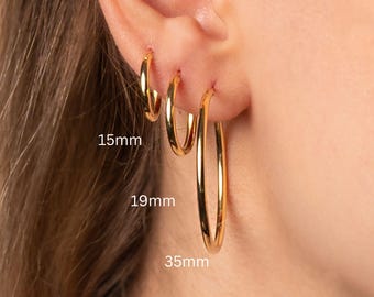 May include: Three gold hoop earrings of different sizes. The smallest hoop is 15mm, the middle hoop is 19mm, and the largest hoop is 35mm.