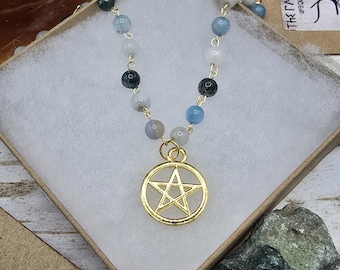 May include: A gold necklace with a pentagram pendant. The necklace is made of small, round beads in shades of blue, green, and white. The pentagram is a five-pointed star.