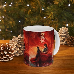 Pode incluir: Caneca de cerâmica branca com uma vibrante ilustração vermelha e laranja com caracteres chineses e figuras em trajes tradicionais. A obra de arte retrata um casal em uma cena dramática. A caneca tem uma alça e interior brancos.
