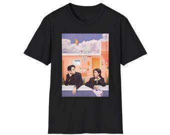 May include: Black t-shirt with a graphic print of a couple standing in front of a building. The text "The Day I Became You" is printed on the graphic.