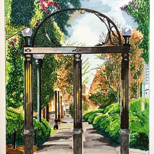 May include: A black wrought iron archway with a curved top and two lampposts on either side. The archway is surrounded by lush green trees and bushes. A paved walkway leads through the archway.