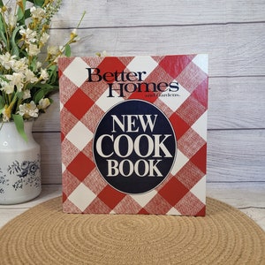 May include: A red and white checkered cookbook with the title "Better Homes and Gardens New Cook Book" in blue lettering.
