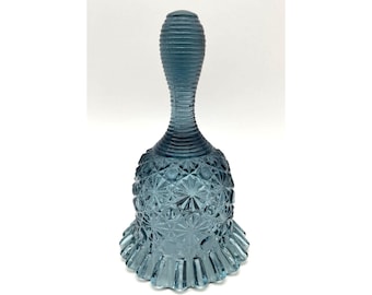 May include: A blue glass bell with a textured handle and a ruffled base. The bell has a detailed, starburst pattern on its body. The bell is a decorative item.