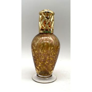May include: A gold and brown glass oil burner with a gold metal cage. The burner has a speckled pattern.