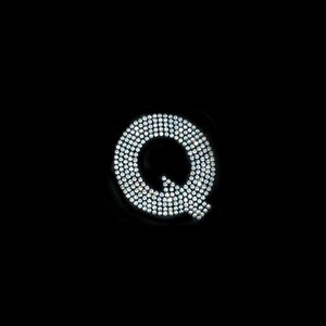 May include: A large letter Q made of small, white, sparkling rhinestones on a black background.