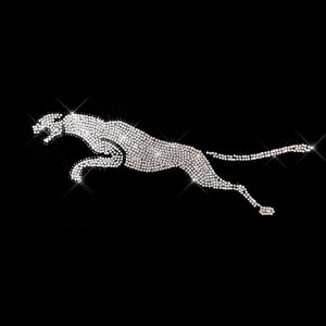 May include: A silver-colored cheetah silhouette made of rhinestones, set against a black background.