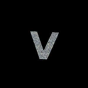 May include: The letter V is formed using small, clear rhinestones on a black background.