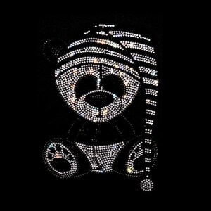 May include: A black and white rhinestone design of a bear wearing a striped sleeping cap.