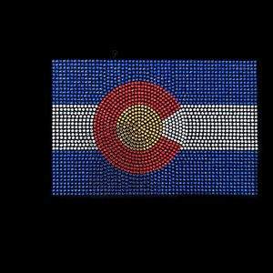 May include: A blue, white, and red Colorado state flag made of rhinestones. The flag is a rectangle with a large circle in the center. The circle is red with a yellow circle in the center.