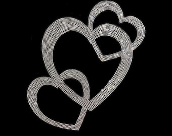 May include: Three interconnected heart shapes, densely covered in sparkling, clear rhinestones, are set against a stark black background. The arrangement creates a layered effect, with each heart overlapping the others, showcasing a dazzling, reflective surface.