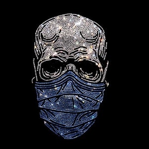 May include: A skull design made of rhinestones, wearing a blue and white face mask. The skull is outlined in silver rhinestones, and the mask is made of smaller, blue and white rhinestones.