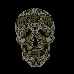 May include: A white and gold sugar skull design with intricate details. The skull is made of rhinestones and is set against a black background.