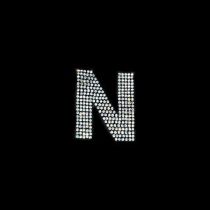May include: The letter N is formed using small, clear rhinestones on a black background.