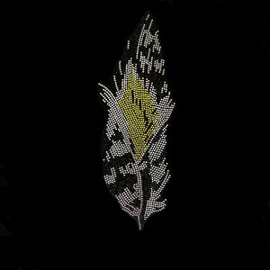Peut inclure: Une plume noire et blanche avec un centre jaune, faite de strass. La plume est un embellissement décoratif.