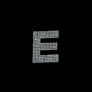 May include: The letter E is formed using small, clear rhinestones on a black background.
